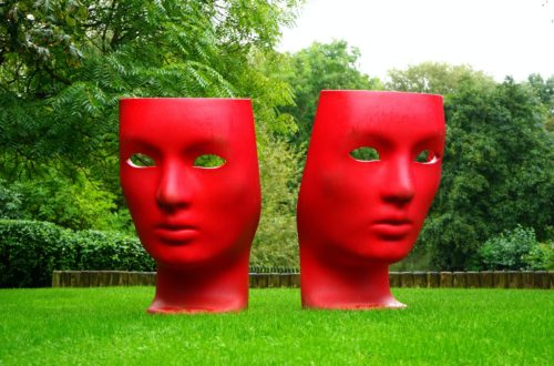 red human face monument on green grass field